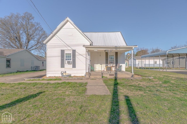 view of front of property featuring central AC, a carport, metal roof, covered porch, and a front lawn