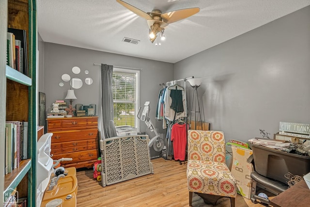 bedroom with a ceiling fan, wood finished floors, and visible vents