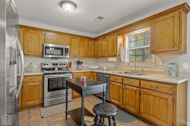 kitchen featuring appliances with stainless steel finishes, decorative backsplash, a sink, and visible vents
