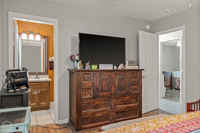 bedroom featuring a sink, light wood-style flooring, and ensuite bath