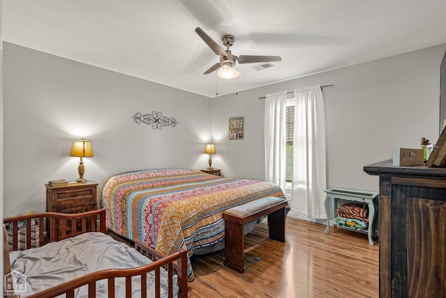 bedroom featuring a ceiling fan, wood finished floors, and visible vents