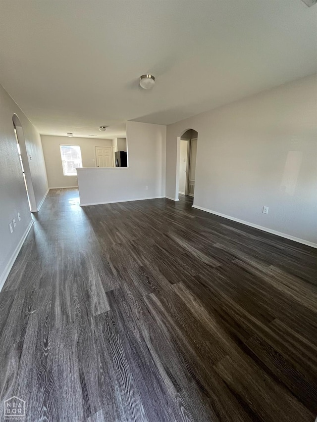 3721 Churchill Dr, Jonesboro, AR 72404 - unfurnished living room with dark wood-style floors, arched walkways, and baseboards