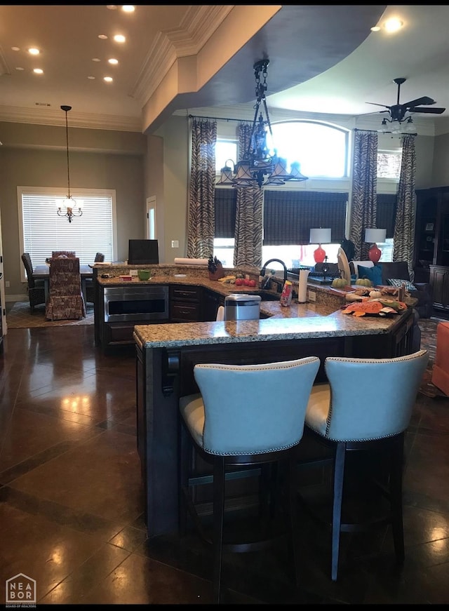 kitchen featuring stone countertops, recessed lighting, pendant lighting, and ceiling fan with notable chandelier