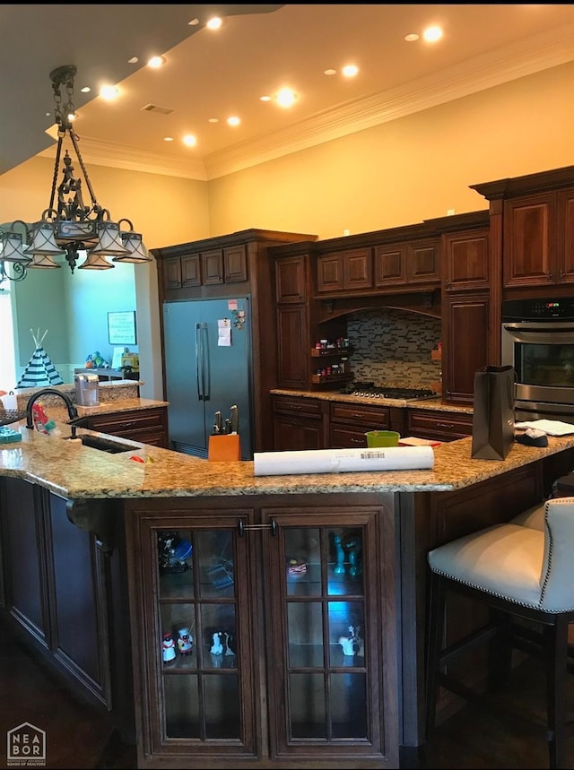 kitchen featuring dark brown cabinetry, glass insert cabinets, stainless steel appliances, a sink, and hanging light fixtures