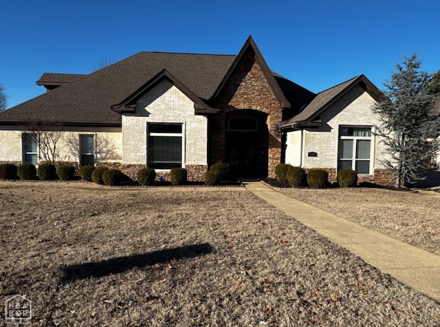 view of front of property with brick siding, stone siding, and a shingled roof