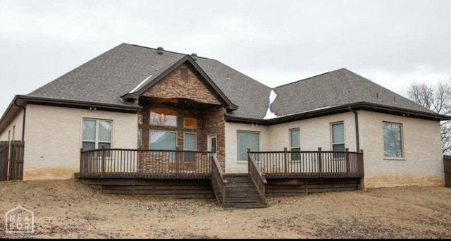 rear view of house with brick siding, a shingled roof, and a deck