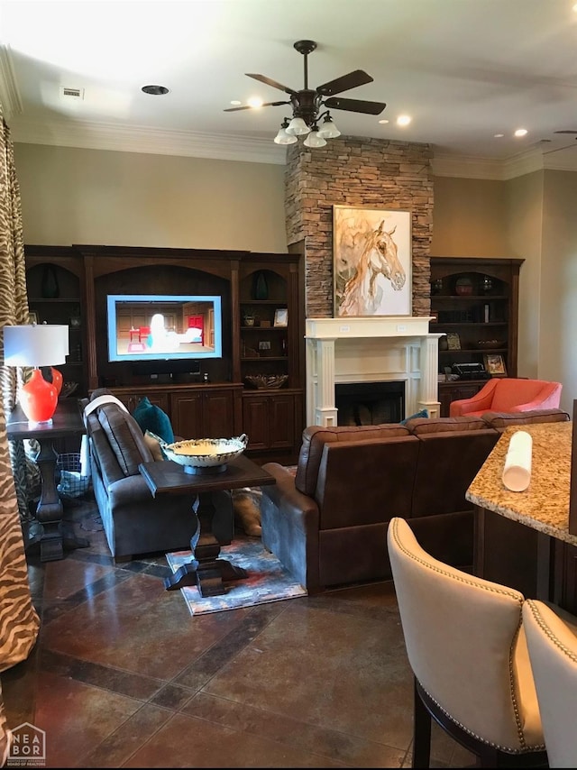 living area with ornamental molding, a ceiling fan, visible vents, and a fireplace