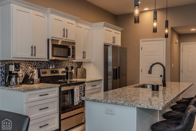 1011 S 59th St S, Paragould, AR 72450 - kitchen with appliances with stainless steel finishes, backsplash, a center island with sink, white cabinetry, and light stone counters