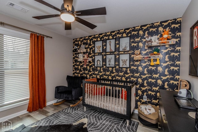 1011 S 59th St S, Paragould, AR 72450 - bedroom with wood finished floors, an accent wall, a ceiling fan, and a crib