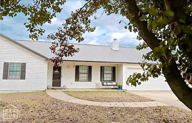 199 County Road 305, Jonesboro, AR 72401 - view of front of home with driveway, a chimney, metal roof, covered porch, and a garage