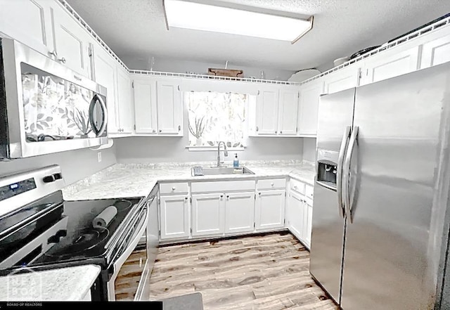 199 County Road 305, Jonesboro, AR 72401 - kitchen featuring white cabinetry, stainless steel appliances, light wood-style floors, and a sink