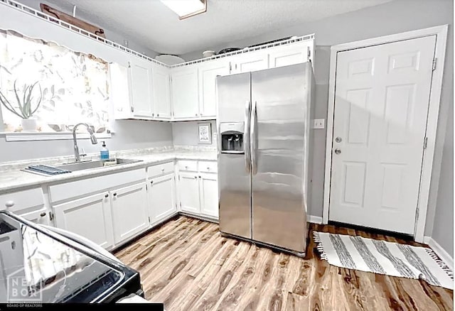 199 County Road 305, Jonesboro, AR 72401 - kitchen with white cabinetry, a sink, light countertops, light wood finished floors, and stainless steel refrigerator with ice dispenser