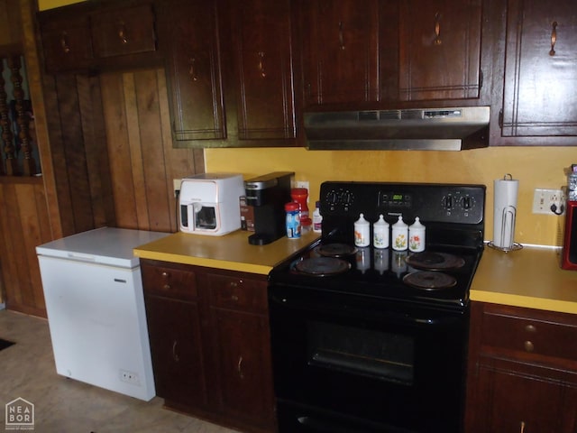 2009 Daugherty St, Newport, AR 72112 - kitchen featuring fridge, under cabinet range hood, light countertops, wood walls, and black range with electric stovetop