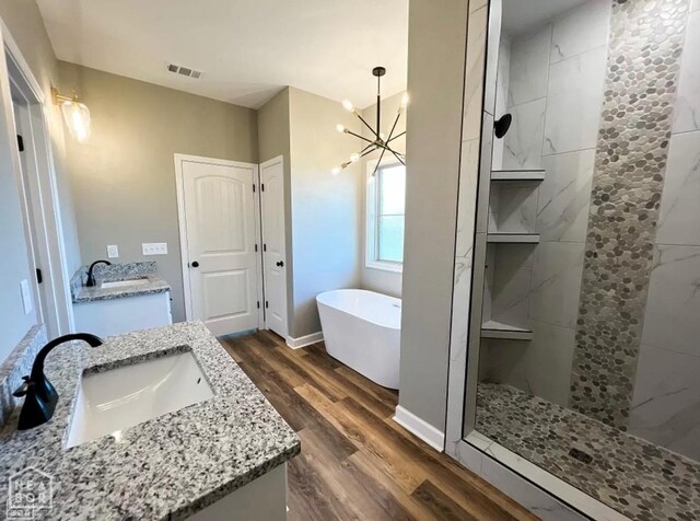 109 Old Eli Rd, Monette, AR 72447 - bathroom featuring wood finished floors, a freestanding tub, vanity, a notable chandelier, and a walk in shower