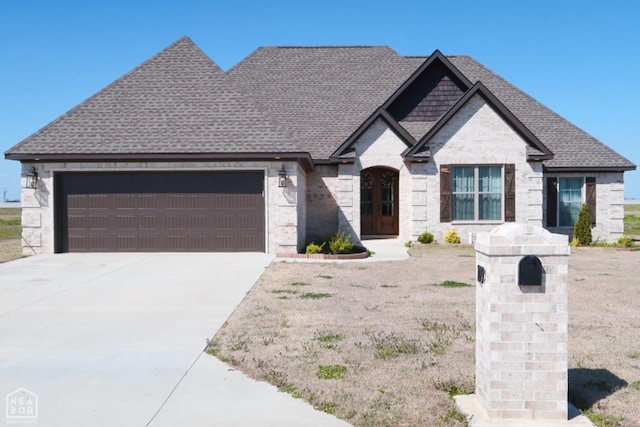 109 Old Eli Rd, Monette, AR 72447 - french provincial home with an attached garage, stone siding, roof with shingles, and driveway