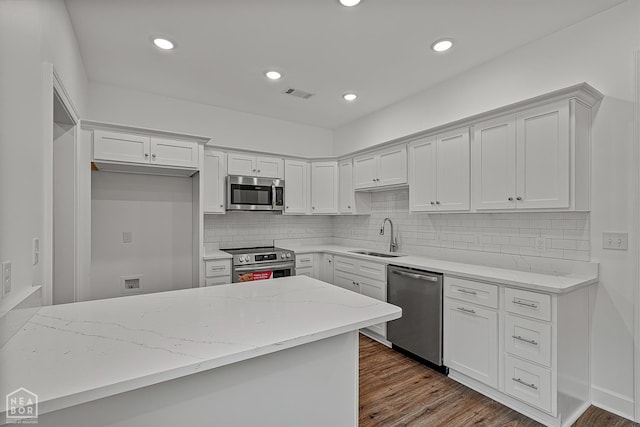 1816 N Oak, Brookland, AR 72417 - kitchen with appliances with stainless steel finishes, light stone countertops, white cabinetry, decorative backsplash, and recessed lighting