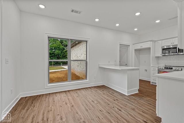 1816 N Oak, Brookland, AR 72417 - kitchen with appliances with stainless steel finishes, light countertops, light wood-style floors, white cabinetry, and decorative backsplash