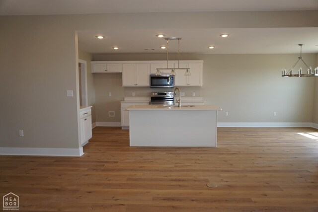 311 Hollis Cv, Bono, AR 72416 - kitchen with appliances with stainless steel finishes, a sink, wood finished floors, and white cabinetry