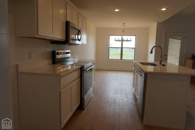 311 Hollis Cv, Bono, AR 72416 - kitchen with stainless steel appliances, a sink, light wood-style flooring, white cabinets, and a chandelier