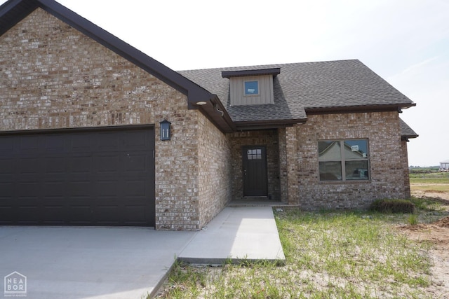 311 Hollis Cv, Bono, AR 72416 - view of front of home featuring brick siding, a garage, driveway, and roof with shingles