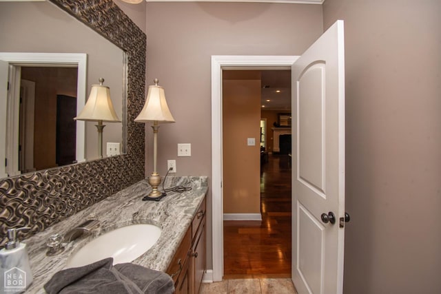 bathroom featuring decorative backsplash, baseboards, vanity, and wood finished floors