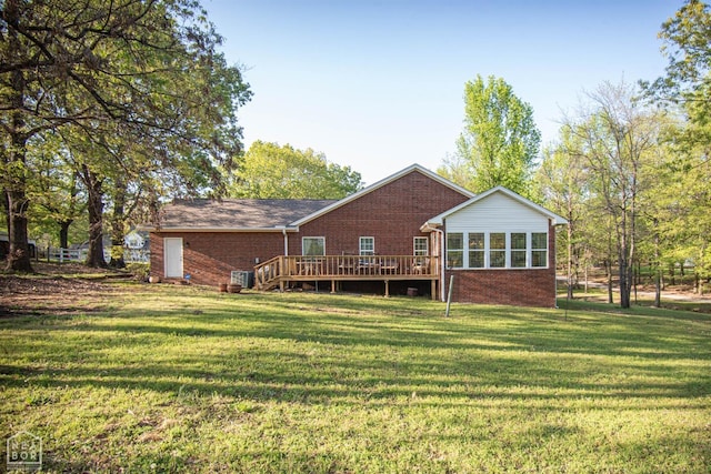 back of property with brick siding, a yard, central AC unit, and a deck