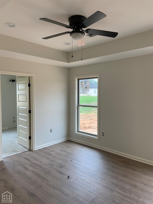 unfurnished room with a ceiling fan, baseboards, and wood finished floors