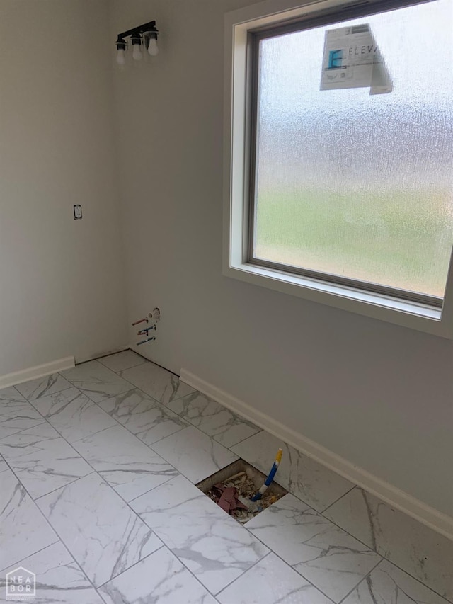 unfurnished room featuring baseboards, marble finish floor, and a wealth of natural light