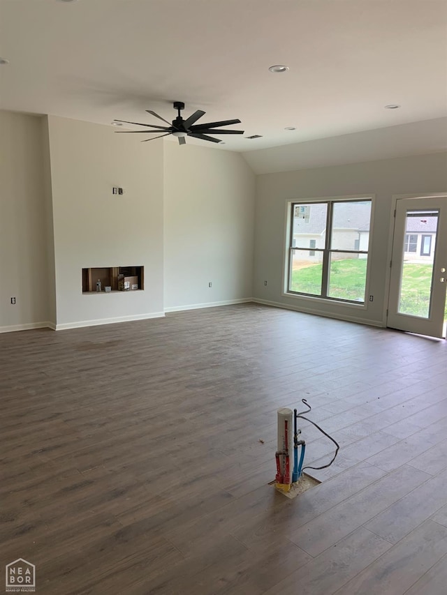 unfurnished living room with baseboards, wood finished floors, and a wealth of natural light