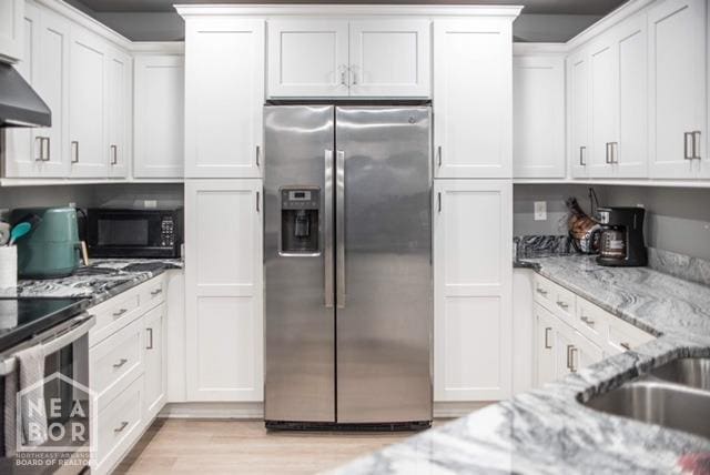 kitchen featuring white cabinets, exhaust hood, light stone counters, and stainless steel appliances