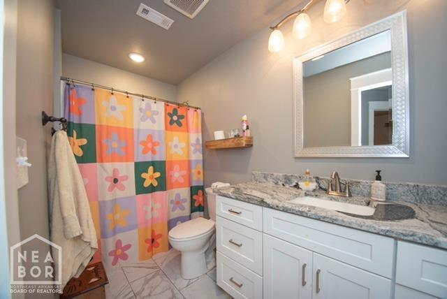 bathroom with toilet, vanity, marble finish floor, and visible vents