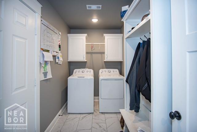 washroom with visible vents, baseboards, washer and dryer, cabinet space, and marble finish floor