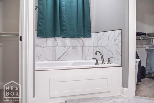 full bath featuring a bathing tub, marble finish floor, and a sink