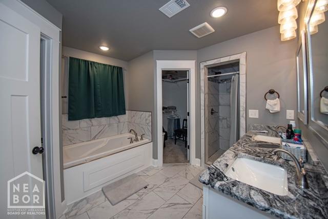 full bath featuring a garden tub, marble finish floor, a sink, and visible vents