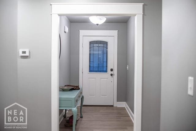 doorway featuring baseboards and wood finished floors
