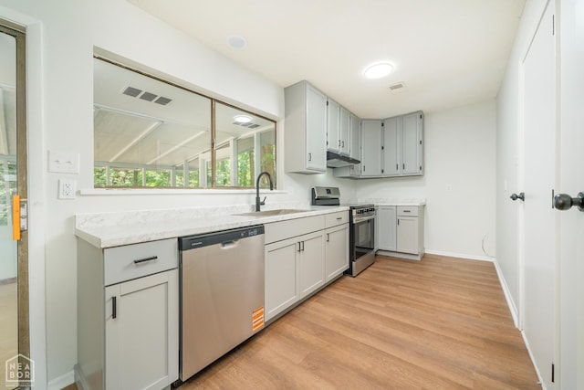 2109 Munos Ln, Jonesboro, AR 72401 - kitchen featuring appliances with stainless steel finishes, a sink, under cabinet range hood, light wood-style floors, and light countertops