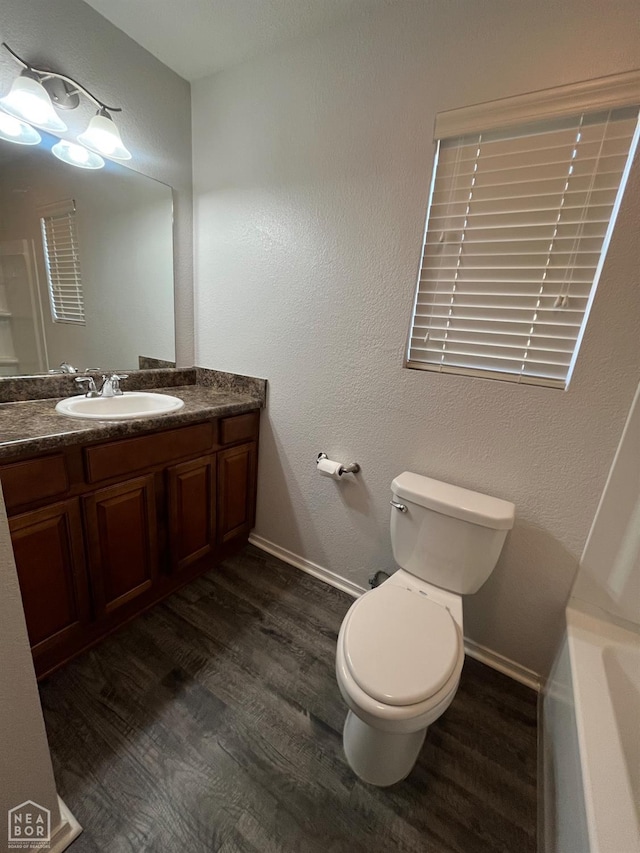 3721 Remington Dr, Jonesboro, AR 72404 - bathroom featuring wood finished floors, toilet, vanity, a tub, and baseboards