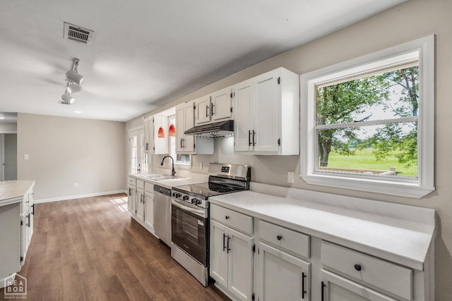 1615 Duncan Rd, Jonesboro, AR 72401 - kitchen with appliances with stainless steel finishes, under cabinet range hood, white cabinetry, light countertops, and wood finished floors