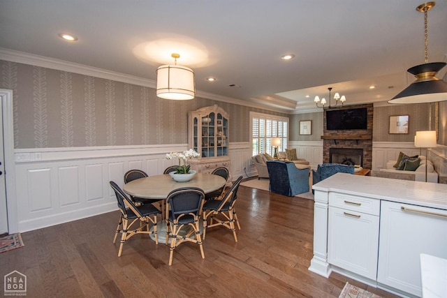 1203 Dove Rd, Jonesboro, AR 72401 - dining area featuring an inviting chandelier, ornamental molding, dark wood finished floors, a stone fireplace, and wainscoting
