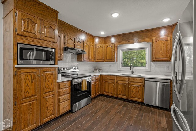 1766 Greene Road 326, Bono, AR 72416 - kitchen with stainless steel appliances, under cabinet range hood, a sink, brown cabinets, and light countertops