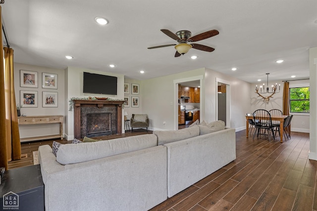 1766 Greene Road 326, Bono, AR 72416 - living area featuring baseboards, a lit fireplace, ceiling fan, dark wood finished floors, and a chandelier