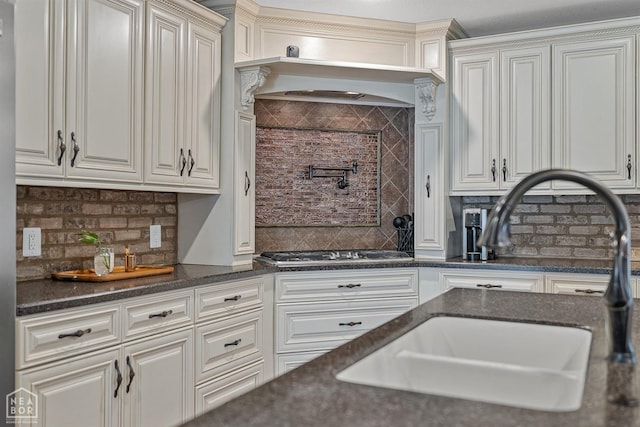 1616 Neely Rd, Jonesboro, AR 72404 - kitchen featuring white cabinets, stainless steel gas cooktop, decorative backsplash, and a sink