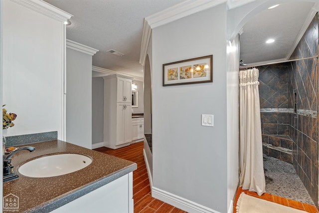 1616 Neely Rd, Jonesboro, AR 72404 - bathroom with crown molding, wood finished floors, vanity, a tile shower, and visible vents
