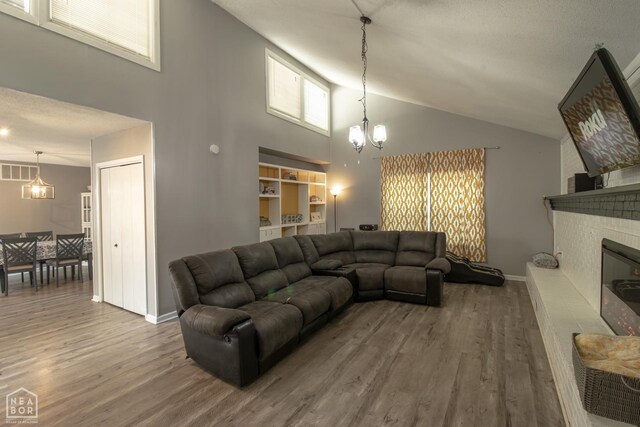 1705 Loberg Ln, Jonesboro, AR 72401 - living area featuring a chandelier, wood finished floors, high vaulted ceiling, a brick fireplace, and baseboards