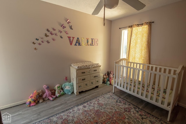 1705 Loberg Ln, Jonesboro, AR 72401 - bedroom with wood finished floors, a ceiling fan, a crib, and a textured ceiling