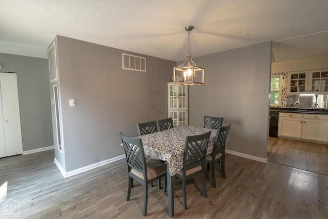 1705 Loberg Ln, Jonesboro, AR 72401 - dining area featuring wood finished floors, a chandelier, baseboards, and a textured ceiling