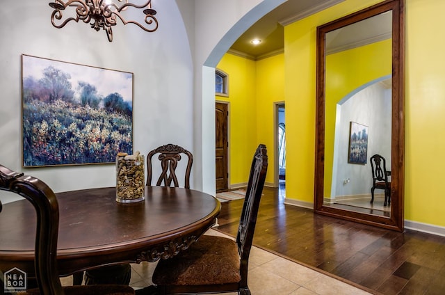 103 Hollis Cv, Bono, AR 72416 - dining area featuring arched walkways, a chandelier, wood finished floors, baseboards, and crown molding