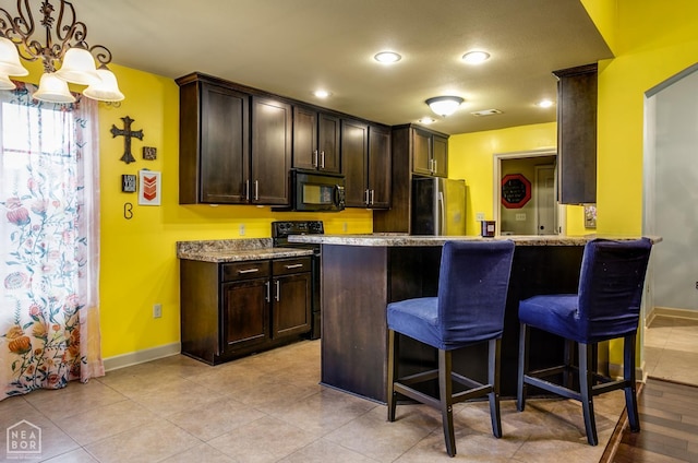 103 Hollis Cv, Bono, AR 72416 - kitchen with black microwave, freestanding refrigerator, range with electric stovetop, dark brown cabinetry, and recessed lighting