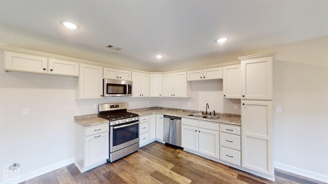 kitchen with baseboards, white cabinets, visible vents, stainless steel appliances, and a sink