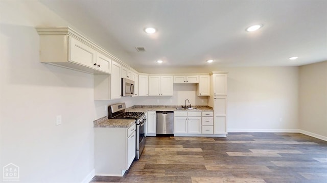 kitchen with dark wood finished floors, visible vents, appliances with stainless steel finishes, a sink, and baseboards